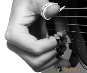 Picking the strings with a thumb pick and finger picks